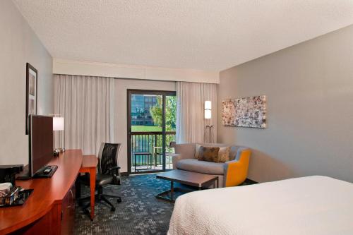 a hotel room with a bed and a desk and a chair at Courtyard by Marriott Charlotte Ballantyne in Charlotte