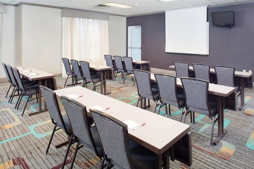 a conference room with tables and chairs and a screen at Residence Inn by Marriott Detroit Livonia in Livonia