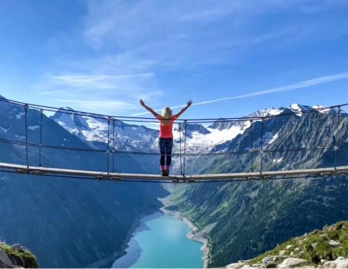 une femme debout sur un pont suspendu au-dessus d'une masse d'eau dans l'établissement Apartment Voithofer, à Wald im Pinzgau