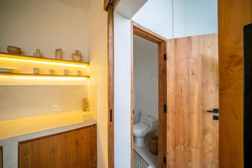 a bathroom with a toilet and a wooden door at Villa Omnia Oasis Two Bedroom Garden Villa in Tumbak Bayuh