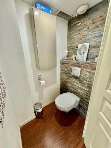 La salle de bains est pourvue de toilettes et d'un mur en briques. dans l'établissement Appartement T4 cœur St-Giniez et parking en ss-sol, à Marseille