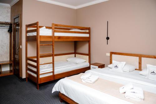 a room with two bunk beds with white sheets at Севеней Готель in Bukovel