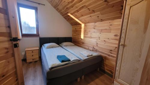 a small bedroom with a bed in a wooden wall at Wrzosowe Wzgórze in Chęciny