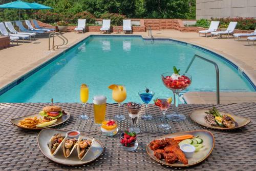 a table with food and drinks next to a swimming pool at The Woodlands Waterway Marriott Hotel and Convention Center in The Woodlands