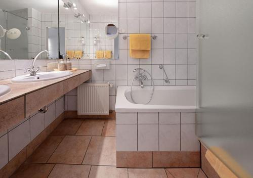 a bathroom with a tub and two sinks and a shower at Hotel Land Gut Höhne in Mettmann