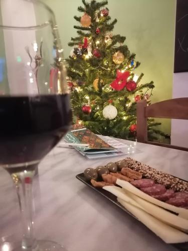a table with a glass of wine and a christmas tree at Ξαπόσταμα XAPOSTAMA - Ενοικιαζόμενα Δωμάτια in Kalyvia