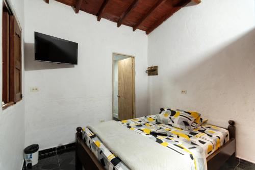 a bedroom with a bed and a tv on the wall at Hotel Orillas del Pizano in Jardin