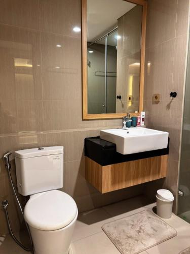 a bathroom with a toilet and a sink and a mirror at Apt Embarcadero 2BR with Netflix & Pool by Damaresa in Pondokpucung