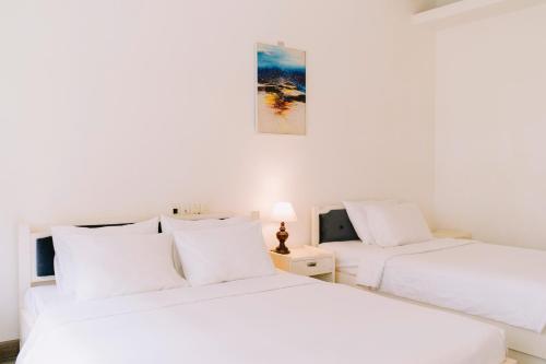 two beds in a room with white walls at Mercury Hotel & Apartment in Vung Tau