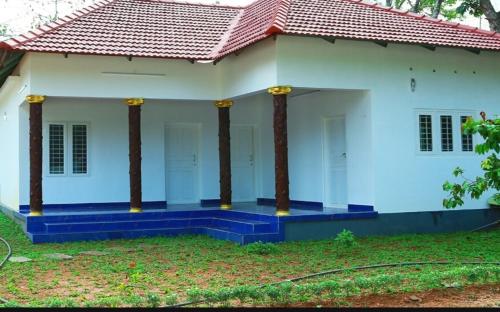 a white house with blue steps and a red roof at Marari ShangriLa Vecation Stay in Alleppey