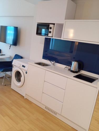 a white kitchen with a washing machine and a sink at Orbi sea view aparthotel in Angisa