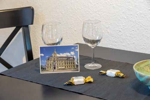 a table with two wine glasses and a picture of a building at Apartment in Uni- und Citynähe in Oldenburg