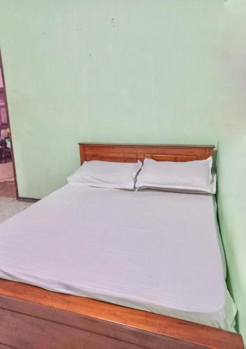 a bed with white sheets and a wooden headboard at Free House Bentota in Bentota