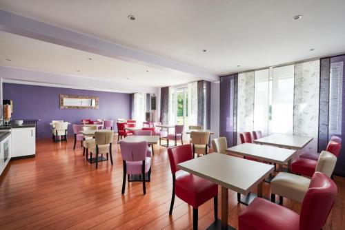 - un restaurant avec des tables et des chaises dans une salle dans l'établissement Cozy Hôtel Logis Morlaix, à Plouigneau
