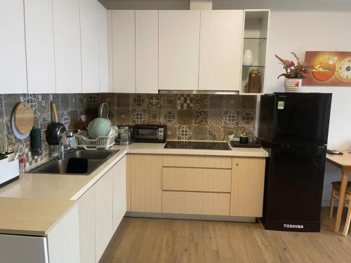 a kitchen with white cabinets and a black refrigerator at Đã đóng cửa in Cong Luận