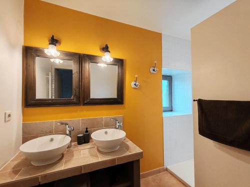 a bathroom with two sinks and two mirrors at La Source Du Bonheur Chambres et Table d'Hôtes in Rieupeyroux