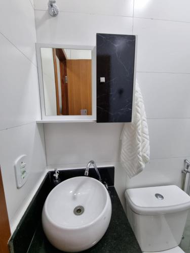 a bathroom with a sink and a toilet and a mirror at Jabuticaba Sabará - Frente ao Mar na Praia de Meaípe, Guarapari in Guarapari