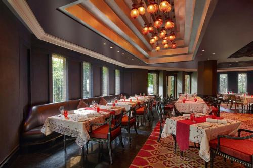 a dining room with tables and chairs and a chandelier at Hyderabad Marriott Hotel & Convention Centre in Hyderabad