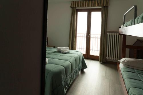 a bedroom with two beds and a window with a balcony at Hotel Galassia in Prato Nevoso