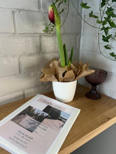 a flower in a vase next to a book on a table at Villa Jalaja in Mäntyharju