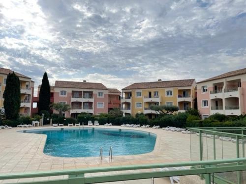 une grande piscine dans une cour avec des bâtiments dans l'établissement Apartment Manon des Sources, à Roquebrune-sur Argens