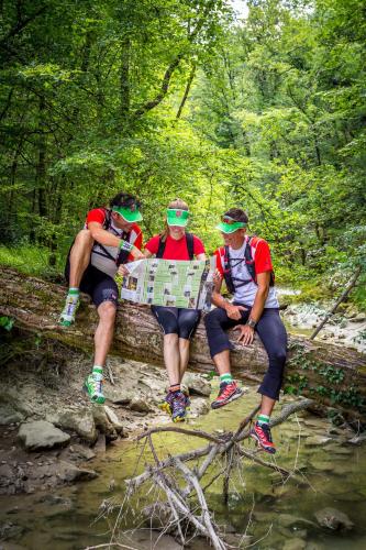 a group of three people sitting on a log over a river at Apartmani Xenia & Desiderio in Buzet