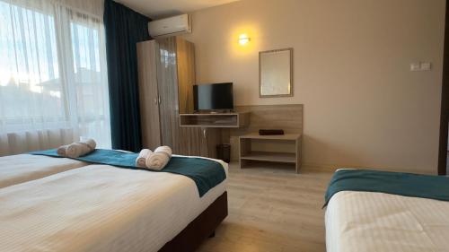 a hotel room with two beds and a television at Семеен хотел БОНЖУР in Panagyurishte