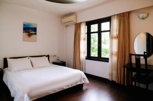 a bedroom with a white bed and a window at Mercury Hotel & Apartment in Vung Tau