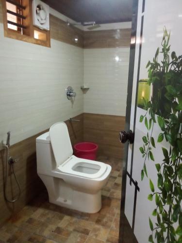 a bathroom with a toilet and a potted plant at River View Guest Rooms in Vythiri