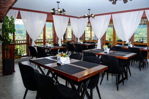 a dining room with tables and chairs and windows at Севеней Готель in Bukovel