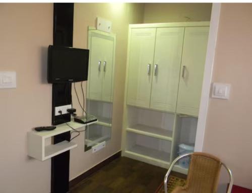 a small room with a tv and some cabinets at Hotel Mothimahal in Trichūr