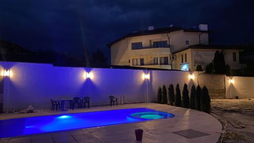 a swimming pool at night with a building in the background at Семеен хотел БОНЖУР in Panagyurishte