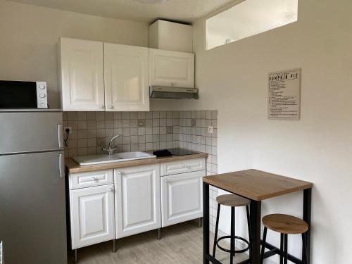 - une cuisine avec des placards blancs, une table et un réfrigérateur dans l'établissement Studio cosy à Évreux - Idéal !, à Évreux