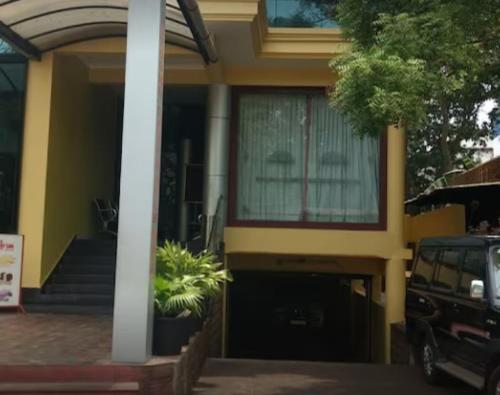 a yellow house with a car parked in front of it at Hotel Mothimahal in Trichūr