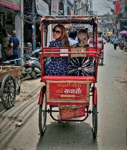 two women riding in a rickshaw on a street at Divine Inn Hotel Near Rajouri Garden Main Market in New Delhi