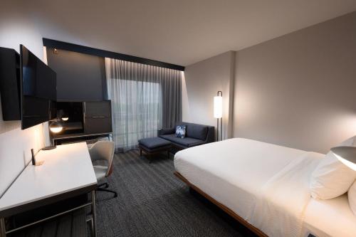 a hotel room with a bed and a chair at Courtyard by Marriott Charlotte Waverly in Charlotte