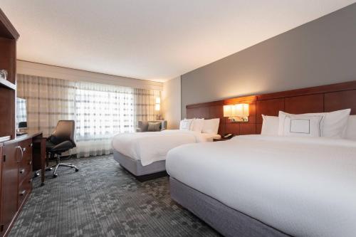 a hotel room with two beds and a desk at Courtyard by Marriott Charlotte Lake Norman in Huntersville