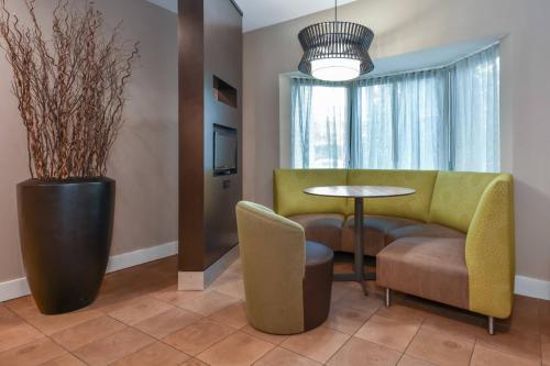a living room with a yellow couch and a table and chairs at Courtyard by Marriott Charlotte Lake Norman in Huntersville