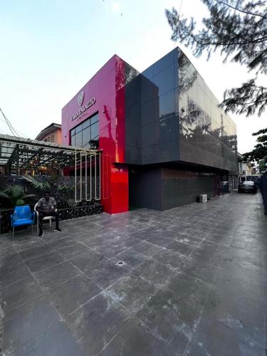 a person sitting on a bench in front of a building at Villa Palazzo Hotel 2 in Ikeja