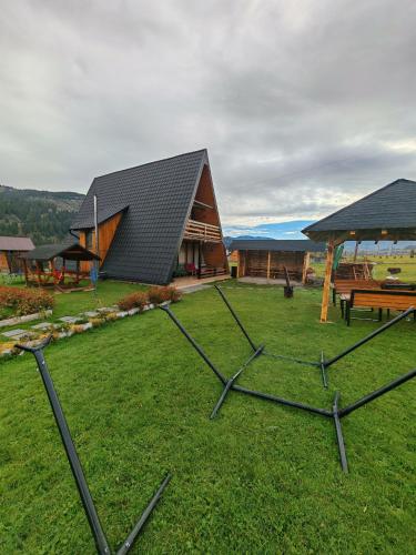 a building with a black roof and a grass field at A Frame Alpin in Vatra Dornei