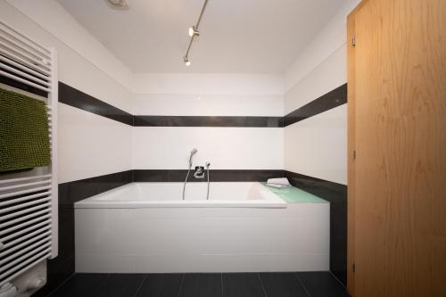a white tub in a bathroom with black and white walls at Arche Ötztal Dorfzentrum in Umhausen
