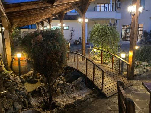 a wooden staircase leading to a house with a pond at Семеен хотел БОНЖУР in Panagyurishte