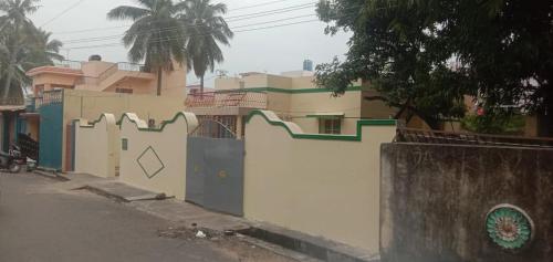 a house with a white fence and a gate at Kriya Home Stays in Tiruvannāmalai