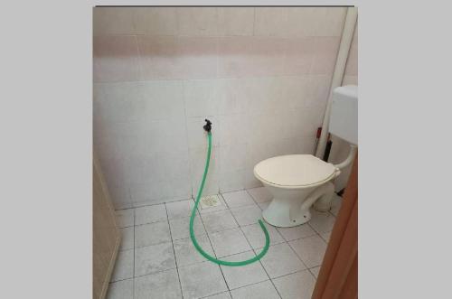 a bathroom with a toilet with a green hose at Mahsuri Homestay in Jitra