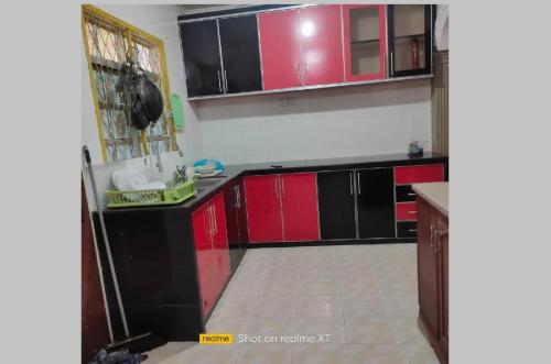 a kitchen with red and black cabinets in a room at Mahsuri Homestay in Jitra