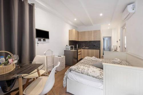 a bedroom with a bed and a table and a kitchen at Le Coccinelle Home in Mandello del Lario