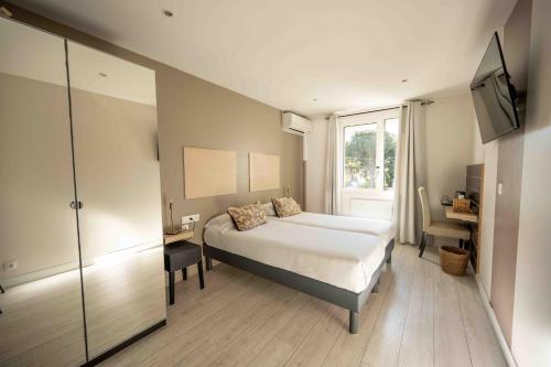 a bedroom with a bed and a window and a television at Hotel La Tuiliere in Carry-le-Rouet