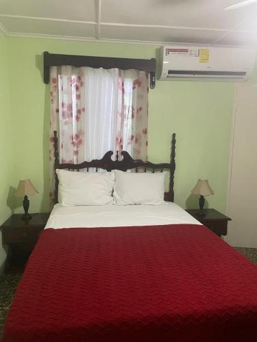 a bedroom with a bed with a red blanket at 6 bedroom KeiraHideaway in Yallahs