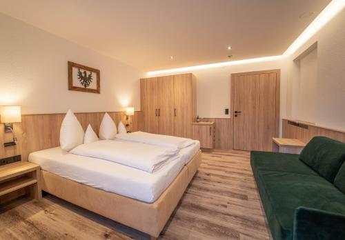 a bedroom with a large white bed and a couch at Hotel Karl Schranz in Sankt Anton am Arlberg