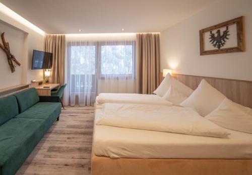 a hotel room with two beds and a couch at Hotel Karl Schranz in Sankt Anton am Arlberg